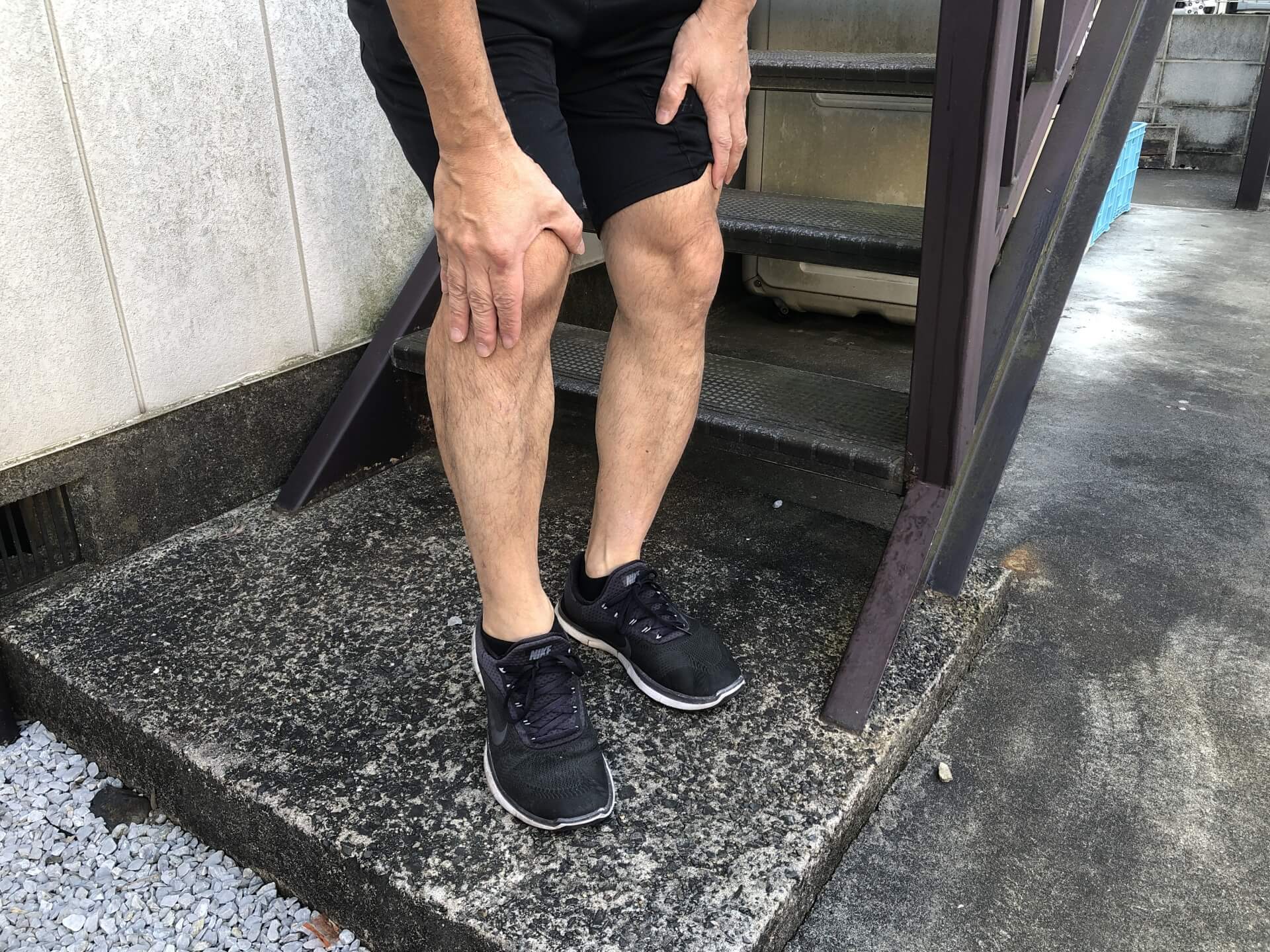 階段のふもとで膝を押さえている男性の足元